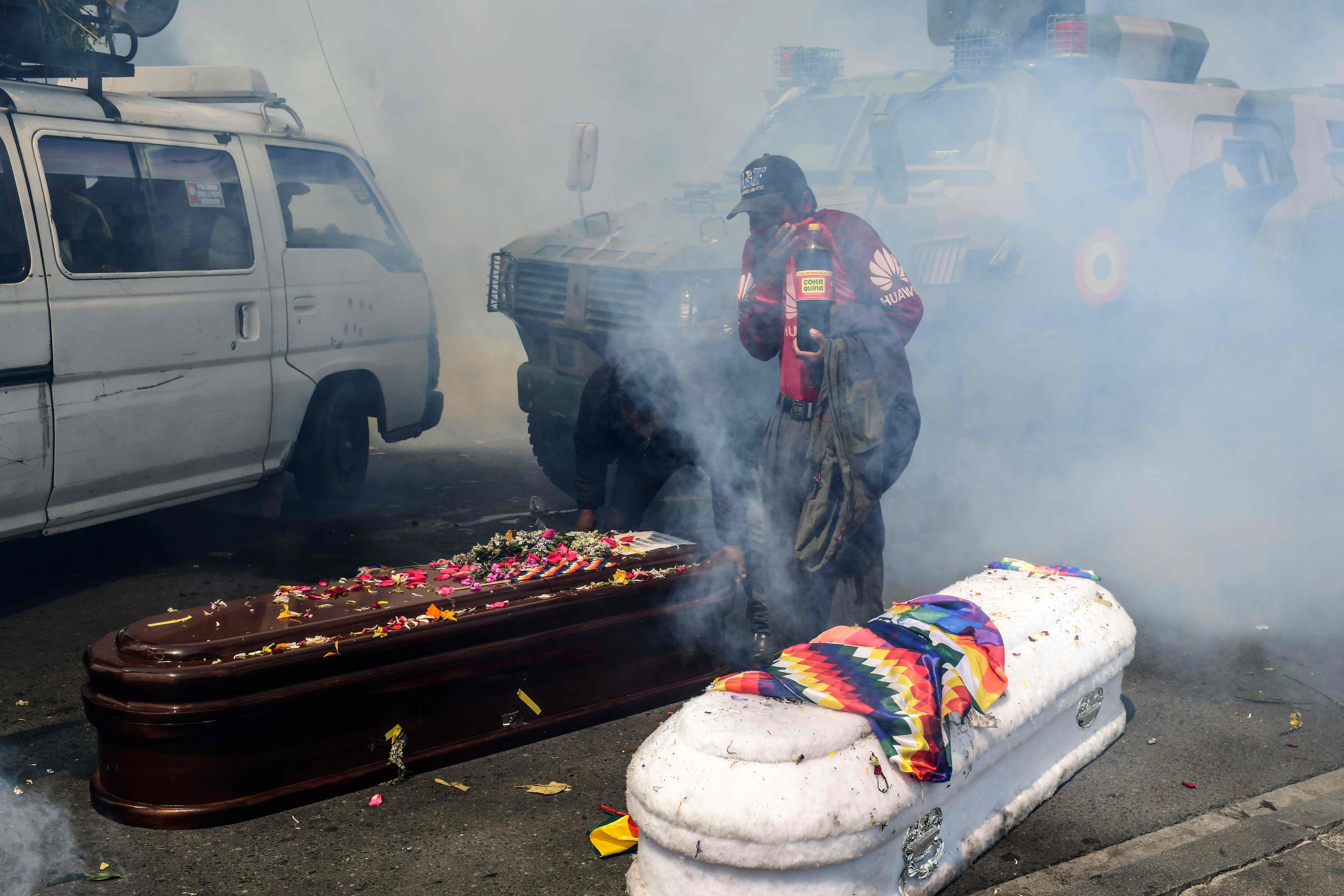 Los familiares de las víctimas muertas corrieron para resguardarse y los ataúdes quedaron en el suelo. (Foto Prensa Libre: AFP)