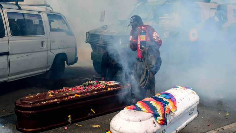 Los familiares de las víctimas muertas corrieron para resguardarse y los ataúdes quedaron en el suelo. (Foto Prensa Libre: AFP)