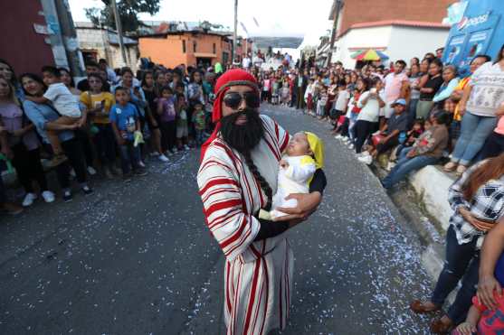 Antes de pasar frente a la Cofradía de Santa Catalina de Alejandría, uno de los personajes muestra a su hijo más pequeño. Foto Prensa Libre: Óscar Rivas