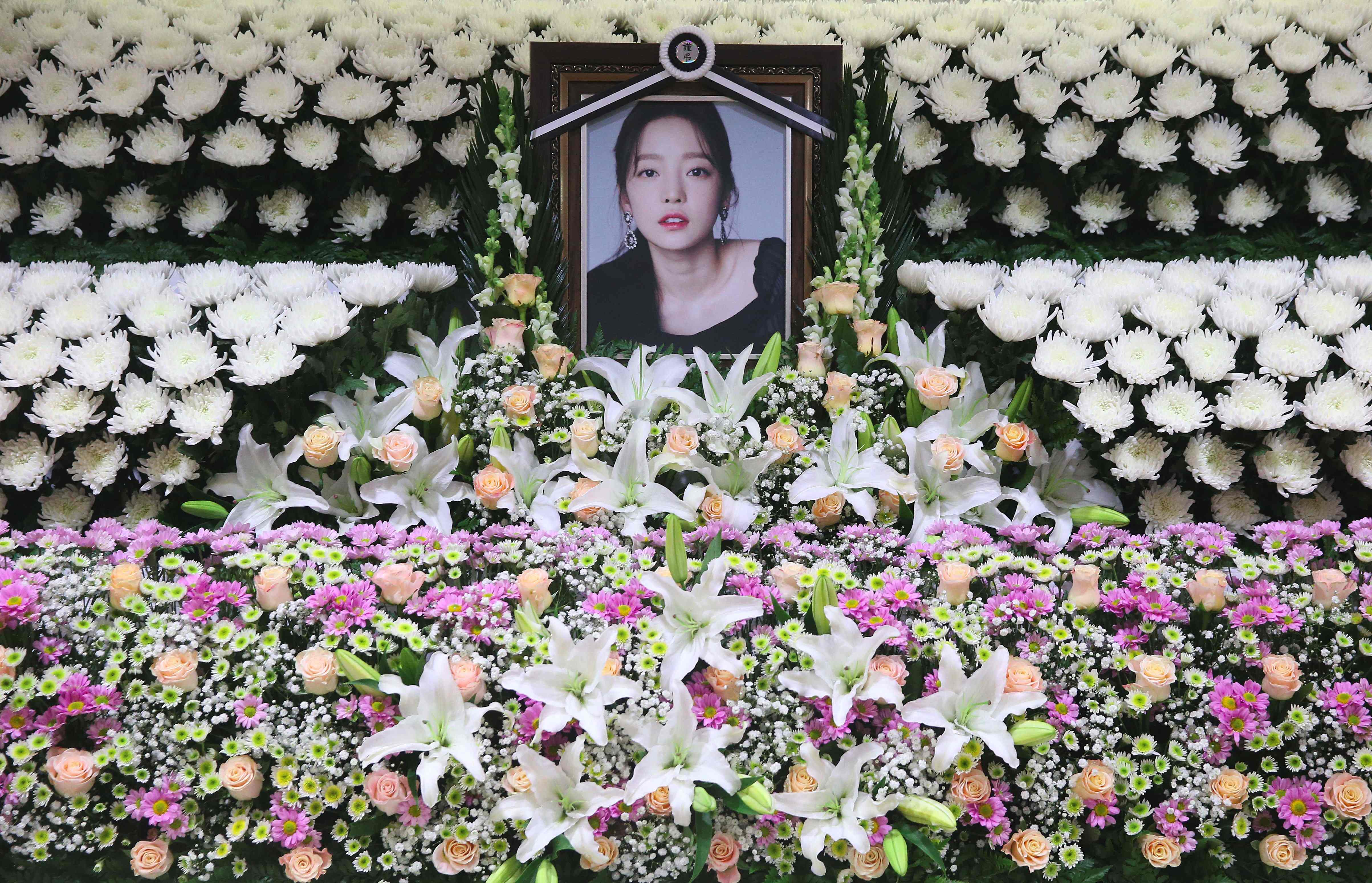 El retrato de la fallecida estrella del K-pop, Goo Hara,  se ve rodeado de flores en un altar conmemorativo en un hospital en Seúl. (Foto Prensa Libre: AFP)