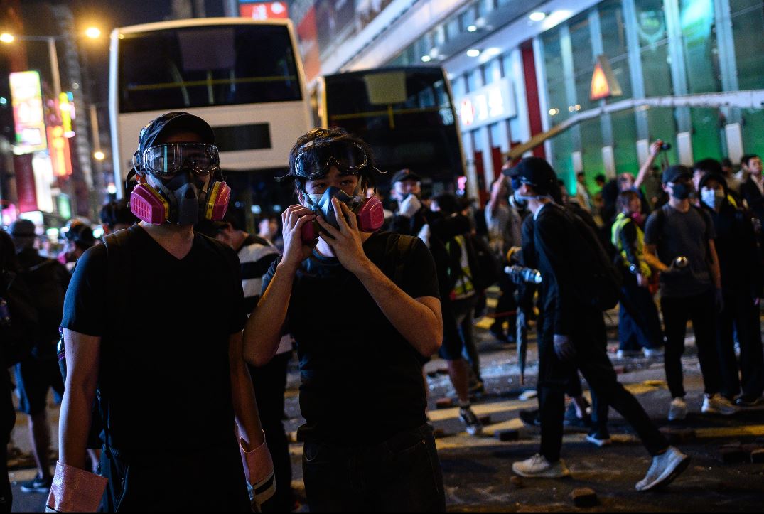 Los manifestantes usan equipo de protección mientras se reúnen en la carretera principal en el distrito Mong Kok de Hong Kong. (Foto Prensa Libre: AFP).  