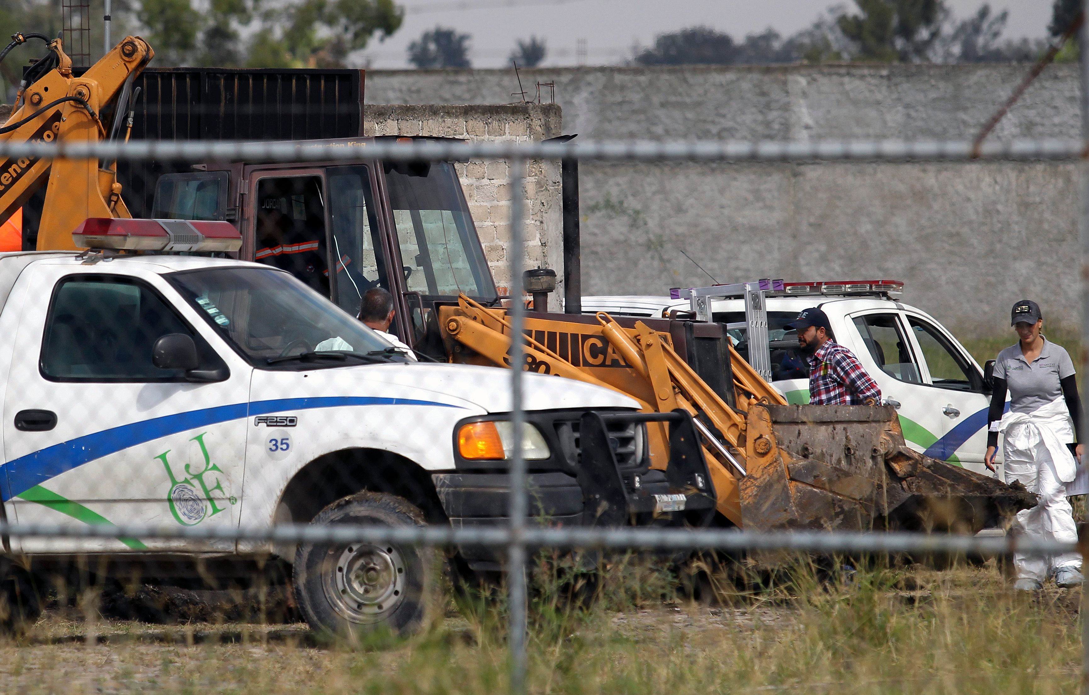 Forenses revisan la finca en la que fueron descubiertos los restos humanos. (Foto Prensa Libre: AFP)
