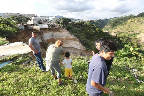 Curiosos tratan de observar los daños a la orilla del derrumbe arriesgando sus vidas. Foto Prensa Libre:  Óscar Rivas