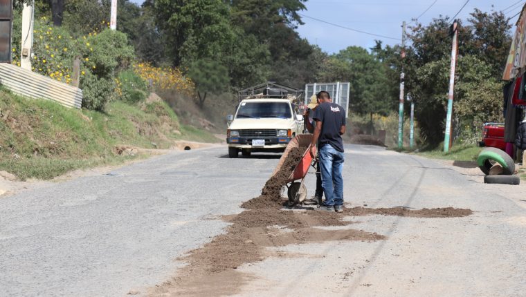 Transportistas rellenan los agujeros en la carretera a San Pedro Jocopilas, Quiché con arena,  (Foto Prensa Libre: Héctor Cordero).