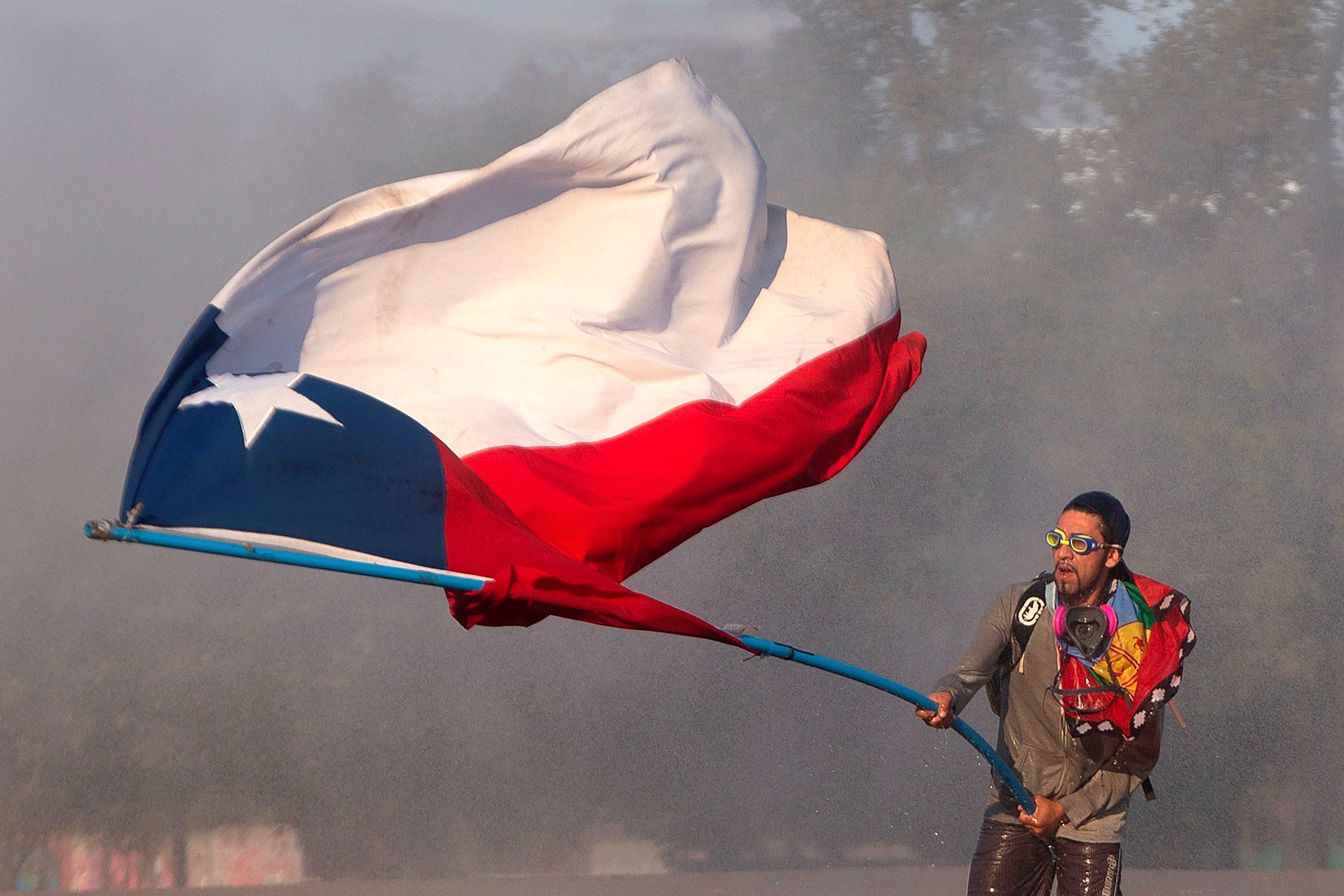 Un ciudadano chileno hondea la bandera nacional en el centro de Santiago de Chile durante las protestas. (Foto Prensa Libre: AFP) 