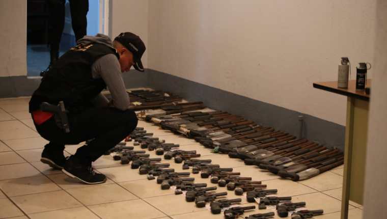 Un agente de la PNC revisa parte de las armas incautadas. (Foto Prensa Libre: PNC)