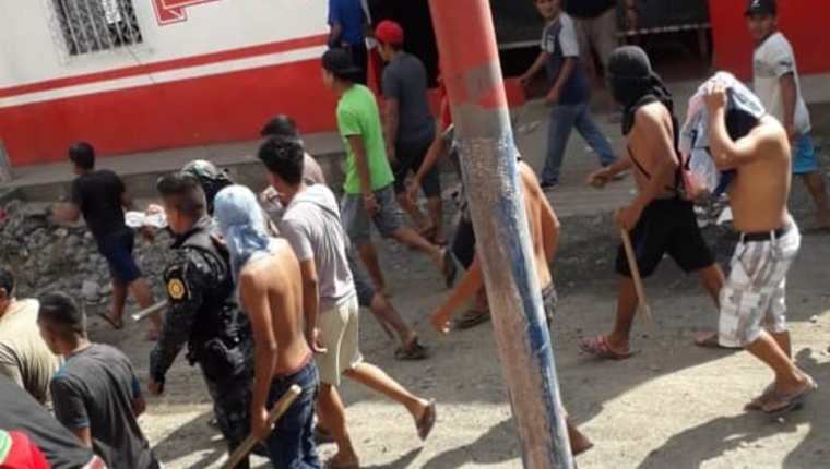 Turba con rostro cubierto y armada de palos toma como rehén a un policía. (Foto Prensa Libre: Cortesía)