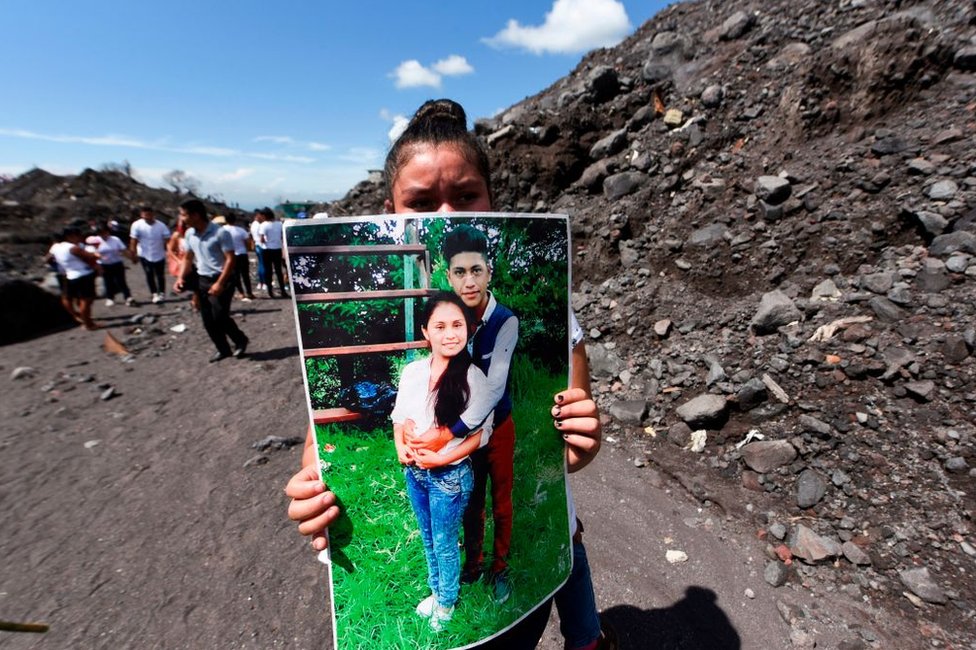 Una mujer sostiene la foto de unos familiares que murieron por la erupción del Volcán de Fuego el 3 de junio de 2018 en el primer aniversario de la tragedia en San Miguel Los Lotes, Guatemala.