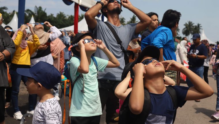 Con protección solar, varios observadores en Malasia disfrutan del eclipse anular. (Foto Prensa Libre: AFP)