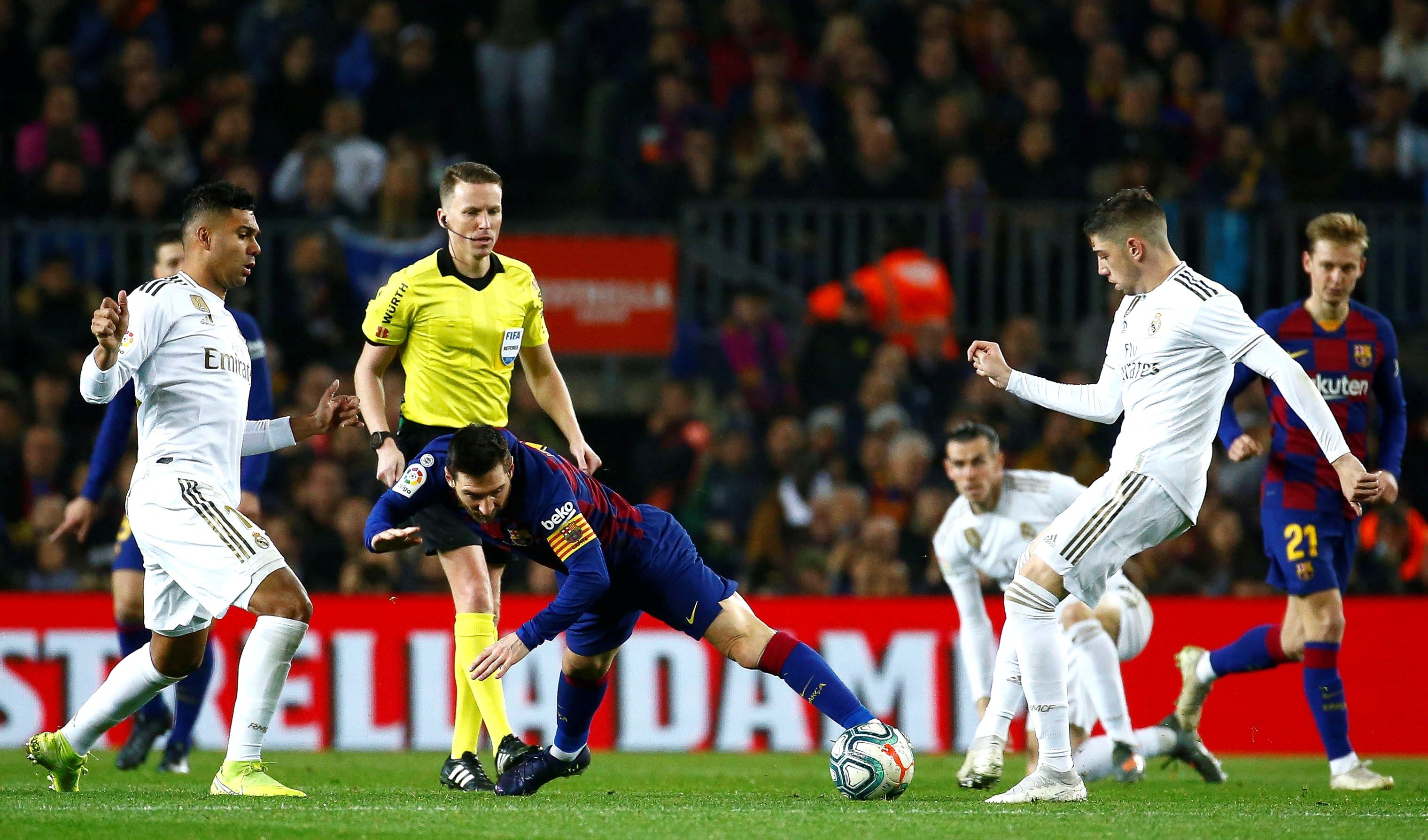 El delantero argentino del FC Barcelona Leo Messi (c) cae entre el brasileño Casemiro (i) y el uruguayo Fede Valverde. (Foto Prensa Libre: EFE)