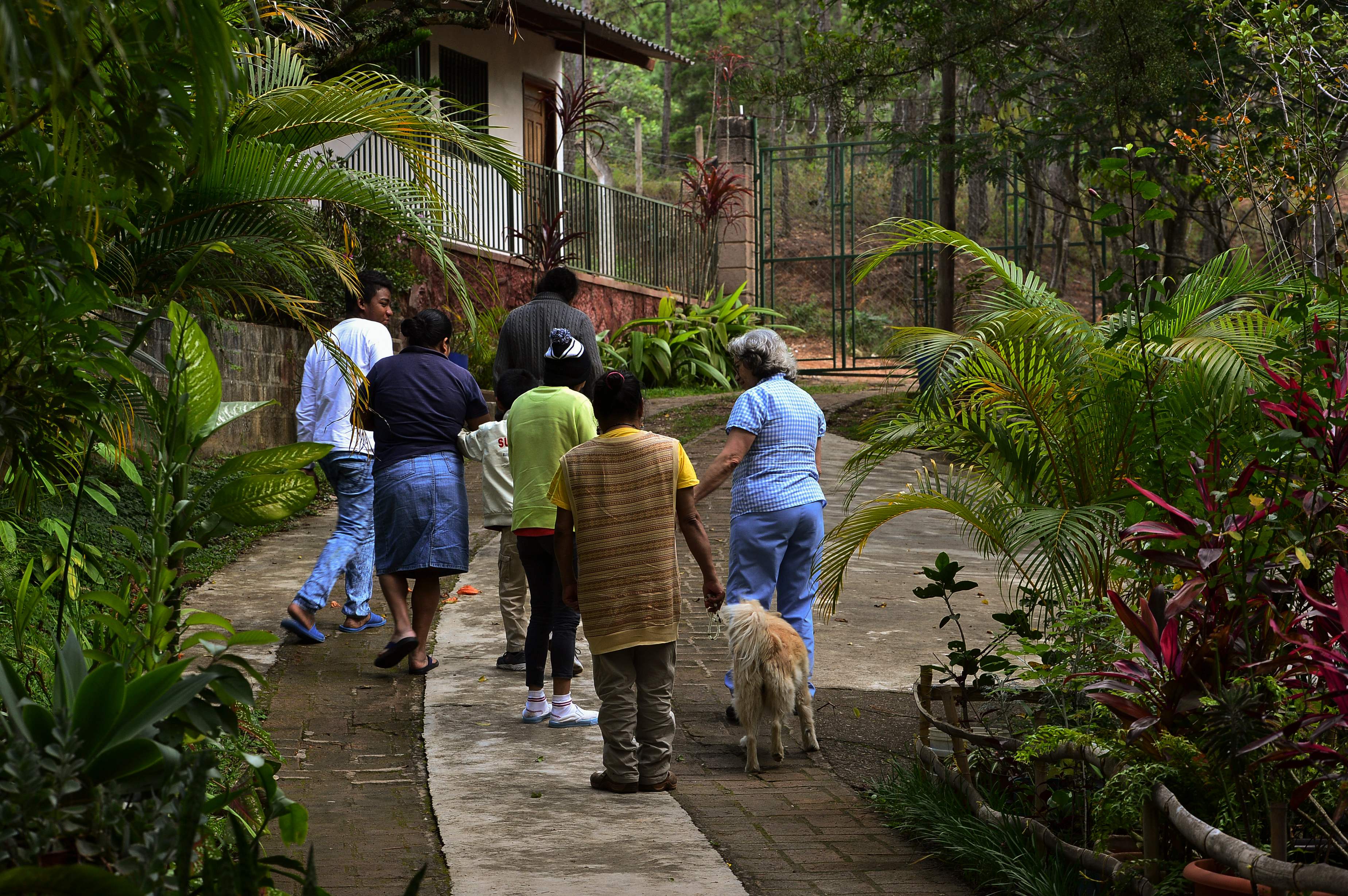 La enfermera Laura Sánchez (derecha) camina con un grupo de portadores de VIH en el refugio Casa Zulema en Honduras. (Foto Prensa Libre: AFP)