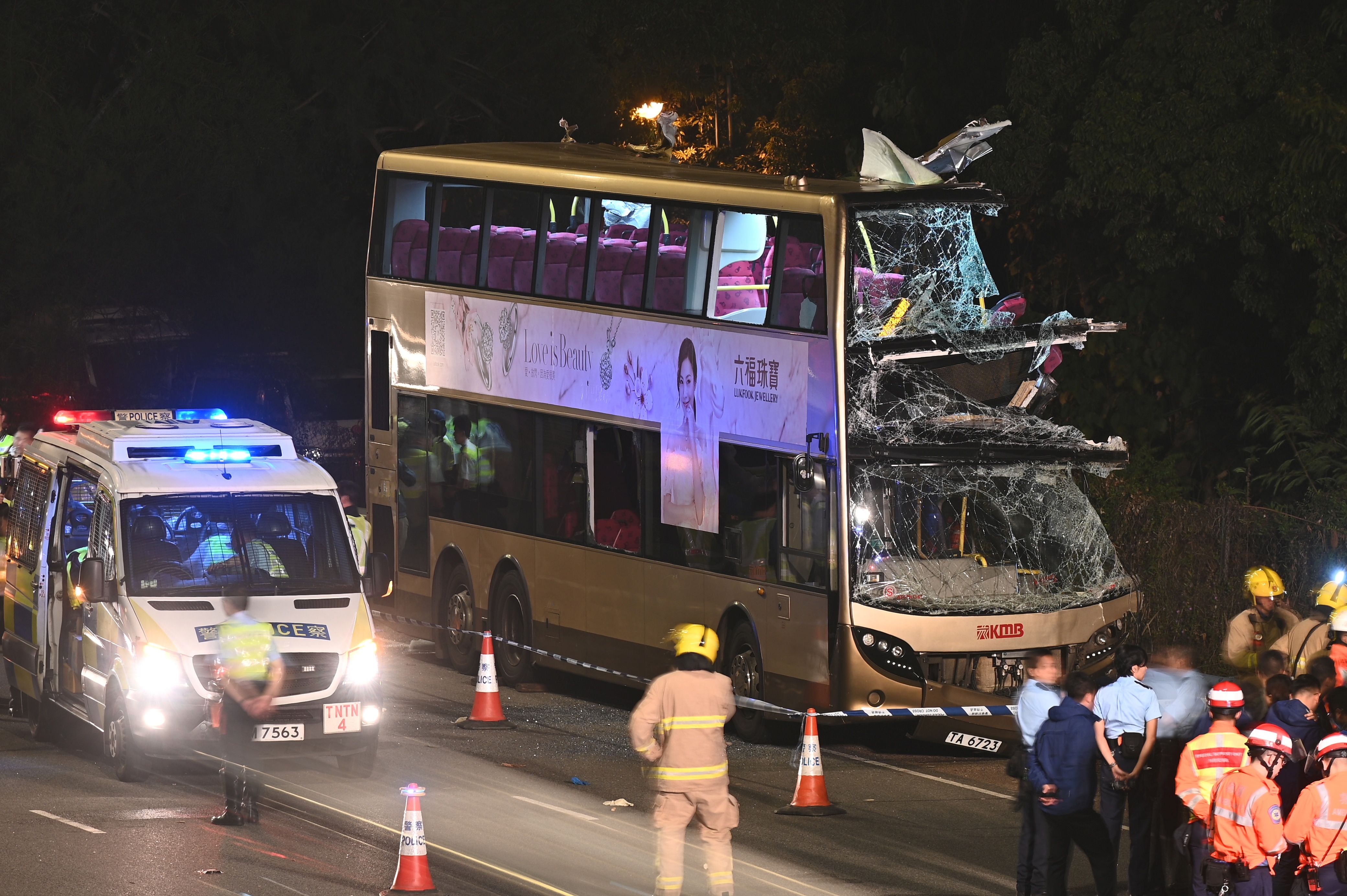 Firefighters, medics and police gather near a double-decker bus after a crash in Kwu Tung in Hong Kong on December 18, 2019. - Six people were killed and dozens injured in Hong Kong on December 18 when a double-decker bus smashed into a tree, police said. (Photo by Philip FONG / AFP)