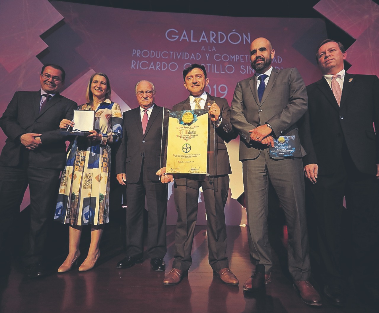 Representantes de la empresa Bayer reciben el Galardón a la Productividad y Competitividad Ricardo Castillo Sinibaldi, quien los acompaña (de traje negro, al medio). (Foto Prensa Libre: Juan Diego González)