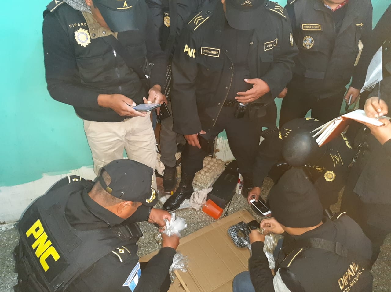 Investigadores y policías revisan los objetos decomisados en la Granja Cantel, Quetzaltenango. (Foto Prensa Libre: PNC) 