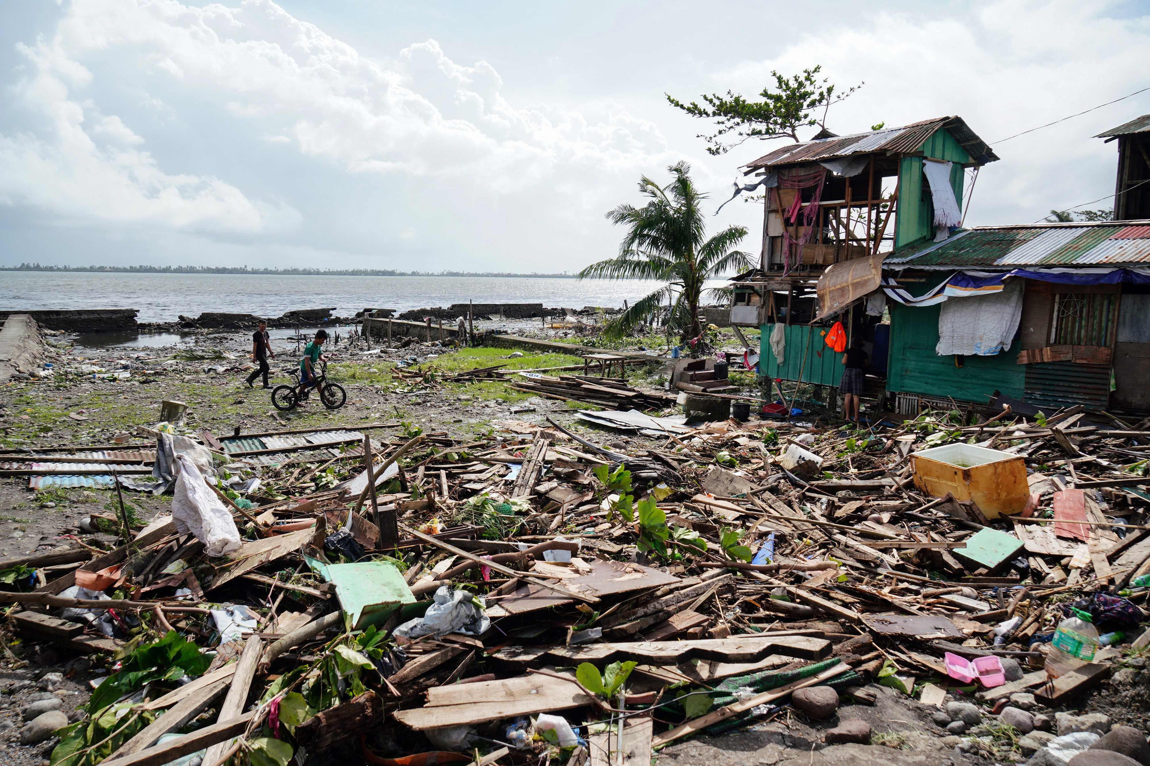 TOPSHOT - Residents walk past a house damaged during Typhoon Phanfone in Tacloban, Leyte province in the central Philippines on December 25, 2019. - Typhoon Phanfone pummelled the central Philippines on Christmas Day, bringing a wet and miserable holiday season to millions in the mainly Catholic nation. (Photo by Bobbie ALOTA / AFP)