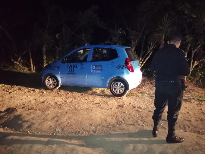 Un agente de la Policía Nacional Civil observa el taxi encontrado en una ruta de terracería en San José Pinula. (Foto Prensa Libre: PNC) 