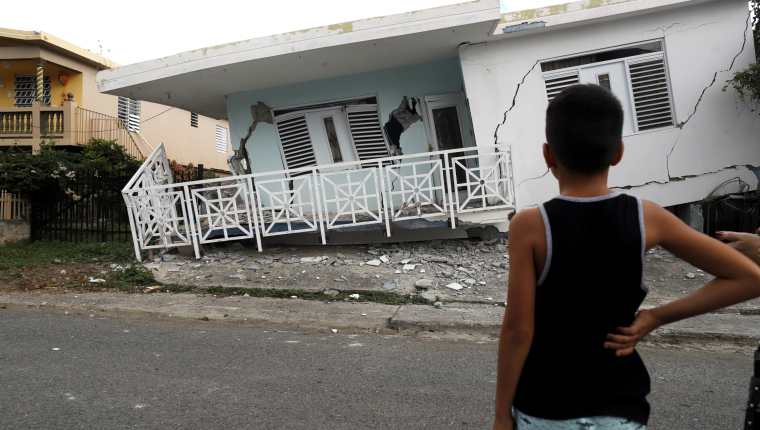 Un niño observa una casa dañada por uno de los temblores. (Foto Prensa Libre: EFE)