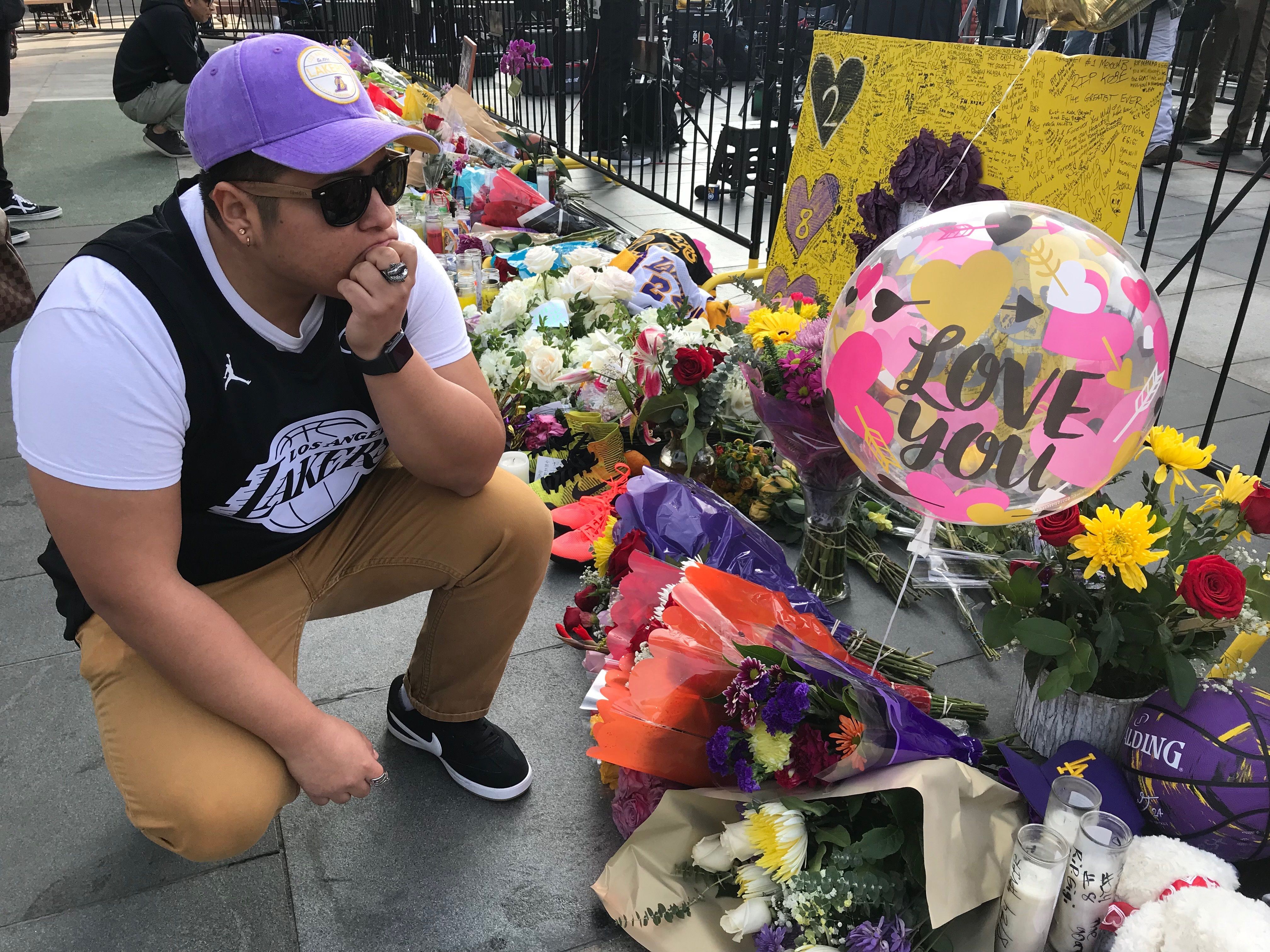 El guatemalteco Eddy Ascencio, de 24 años coloca flores en los altares improvisados para Kobe Bryant, a las afueras del Staples Center. (Foto Prensa Libre: EFE)