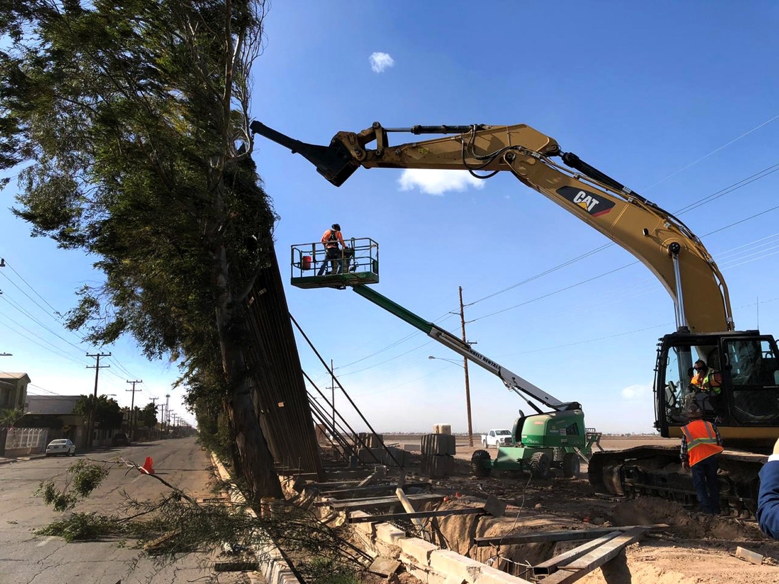 Fotografía cedida por Rafael Torres donde se muestra a una grúa mientras intenta sostener trozos del muro fronterizo que cayeron este miércoles en la frontera de Calexico, California. (Foto Prensa Libre: EFE)