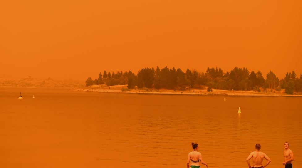 Residentes se dan un chapuzón para refrescarse en el lago Jindabyne, bajo un cielo rojo debido al humo de los incendios forestales, en la ciudad de Jindabyne en Nueva Gales del Sur. (Foto Prensa Libre: AFP).