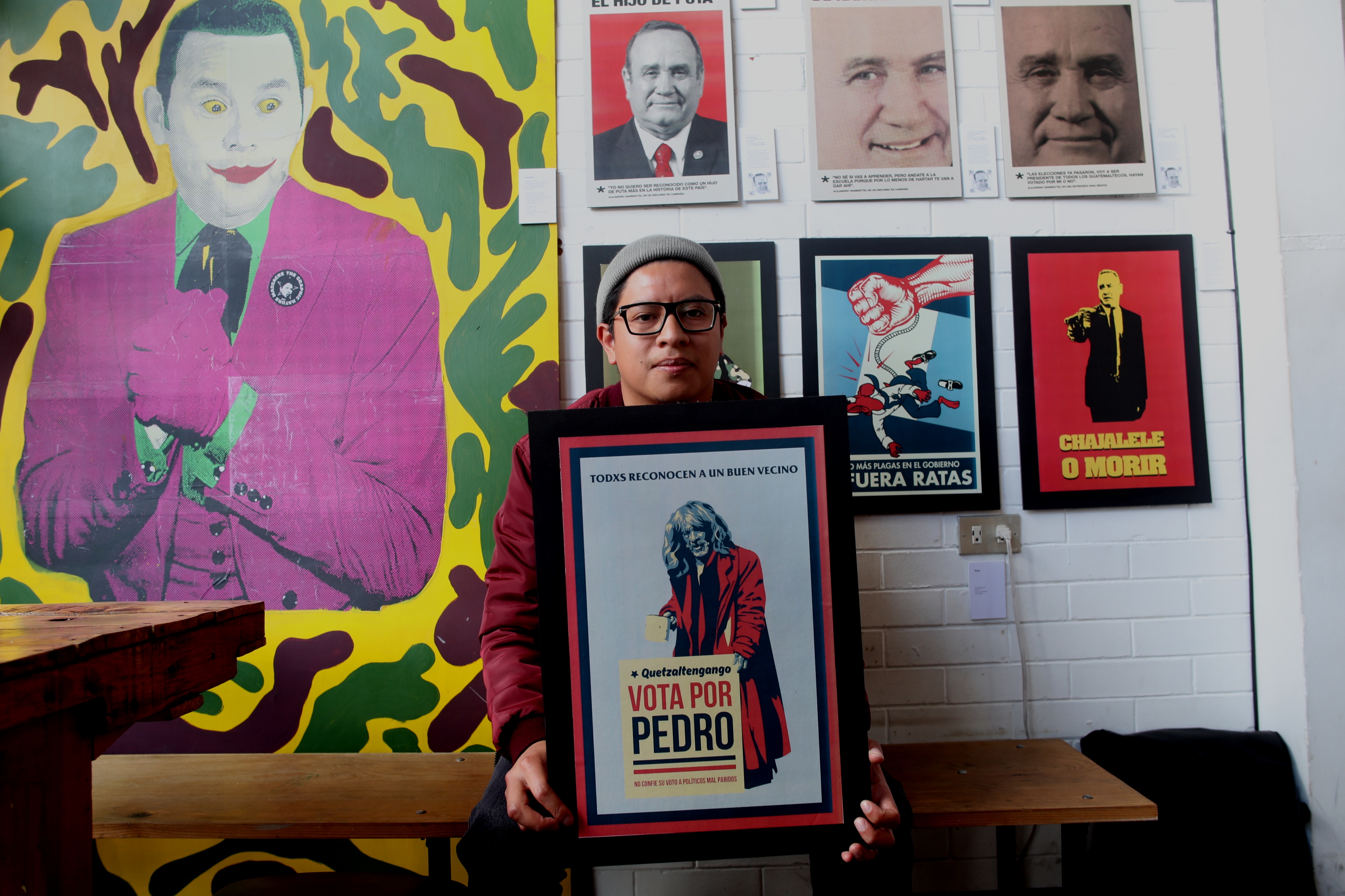 Santiago Lucah sostiene el arte de Pedro Tirapiedras y está rodeado por las otras obras. (Foto Prensa Libre: María Longo) 