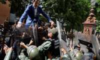 El líder opositor Juan Guaidó trepa una reja en un intento por ingresar a la sede de la Asamblea Nacional, custodiada por la policía para impedir su ingreso. (Foto Prensa Libre: EFE) 