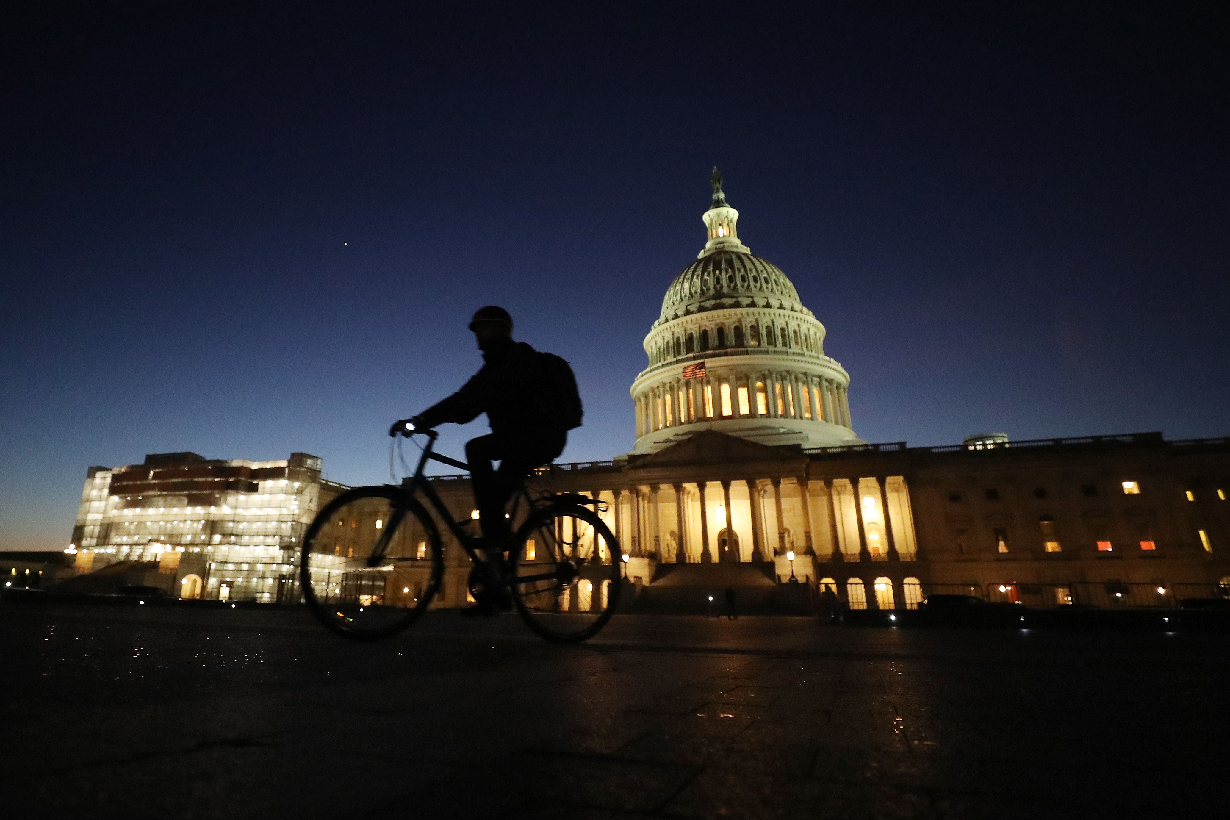 Un ciclista pasa frente al Capitolio durante el comienzo del juicio político contra Trump. (Foto Prensa Libre: AFP)
