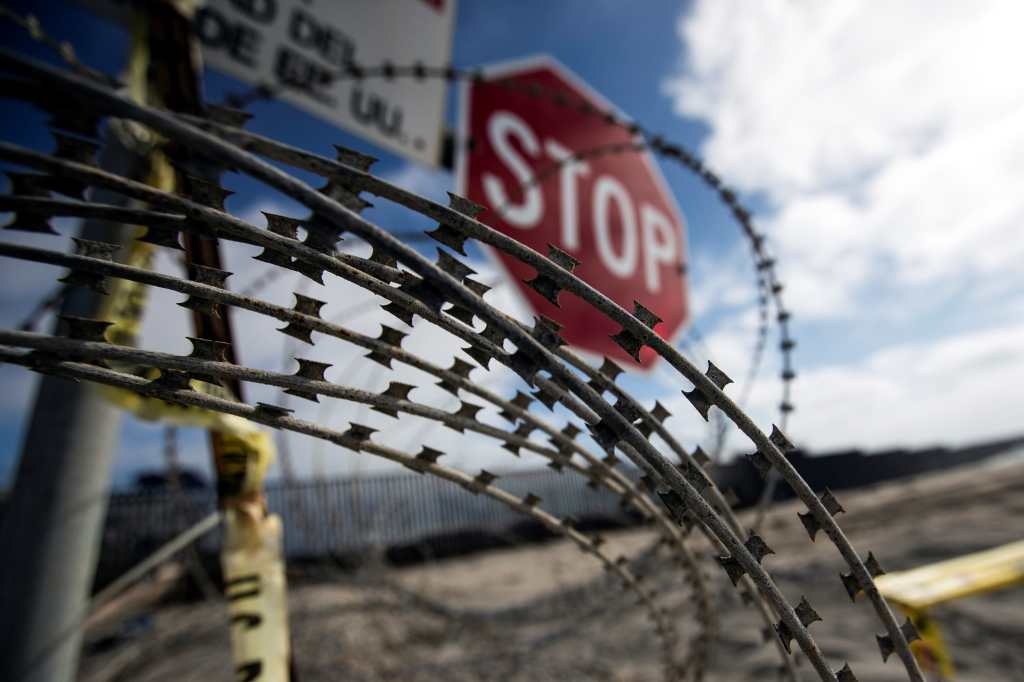 Los alambres y letreros prohíben la entrada a una zona restringida donde el muro que delimita la frontera entre EE.UU.