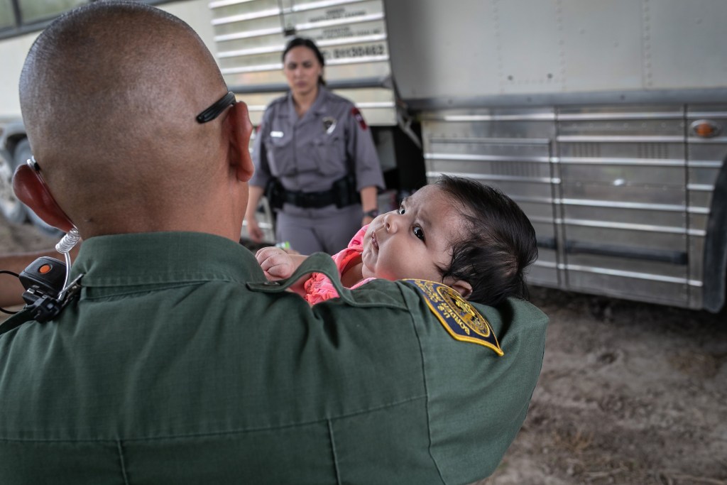Agente toma a una bebé después de que ella y su madre fueron detenidas por agentes de la Patrulla Fronteriza de los EE.UU.