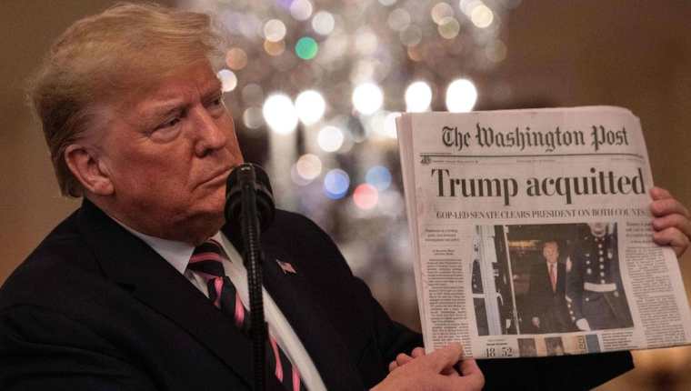 "Absuelto". Trump mostró uno de los diarios que reseñaron el resultado del juicio de impeachment al que fue sometido. AFP