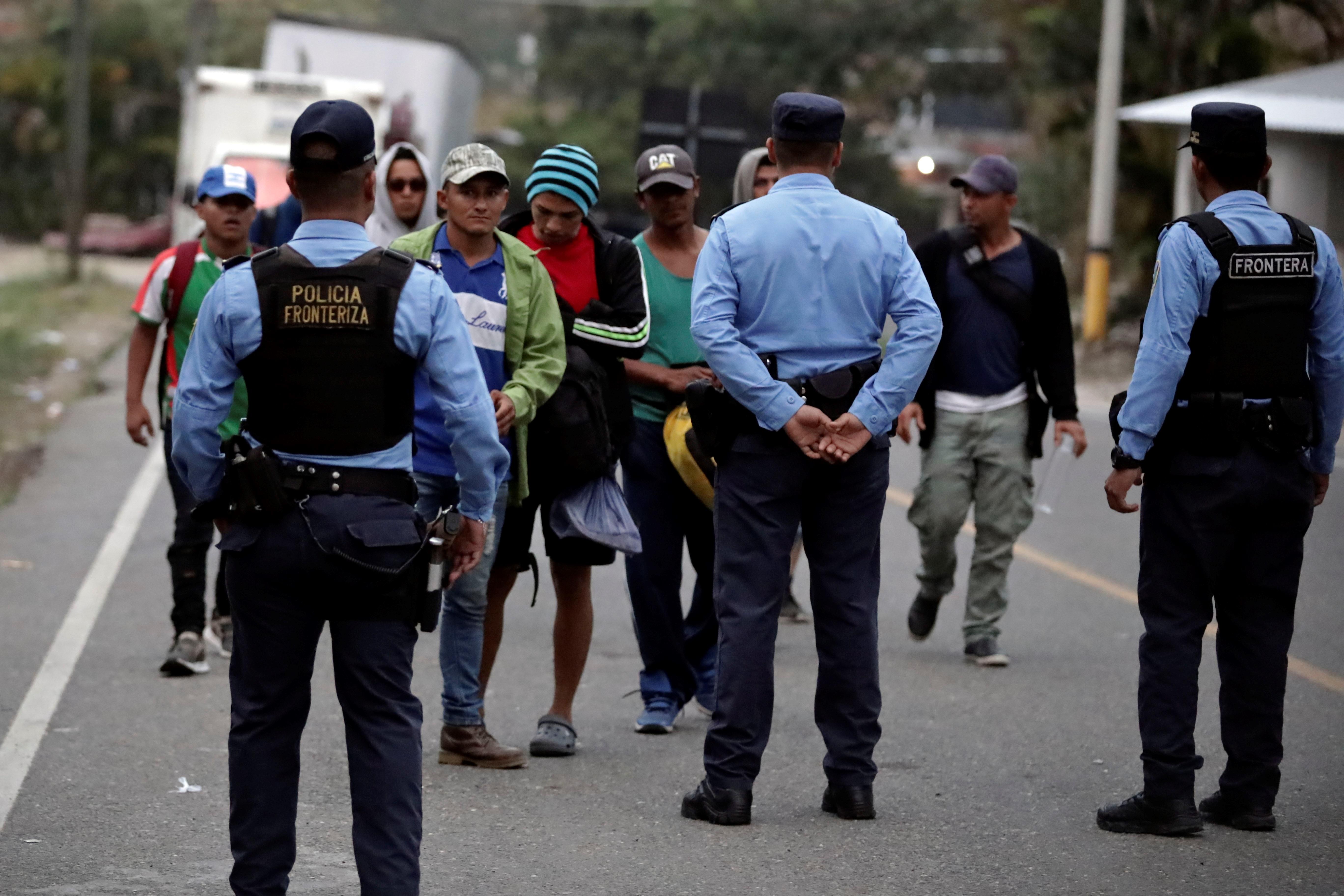 Agentes de policía hondureña verifican los antecedentes de migrantes a personas de una de las caravanas que han pasado por Guatemala. (Foto Prensa Libre: EFE)