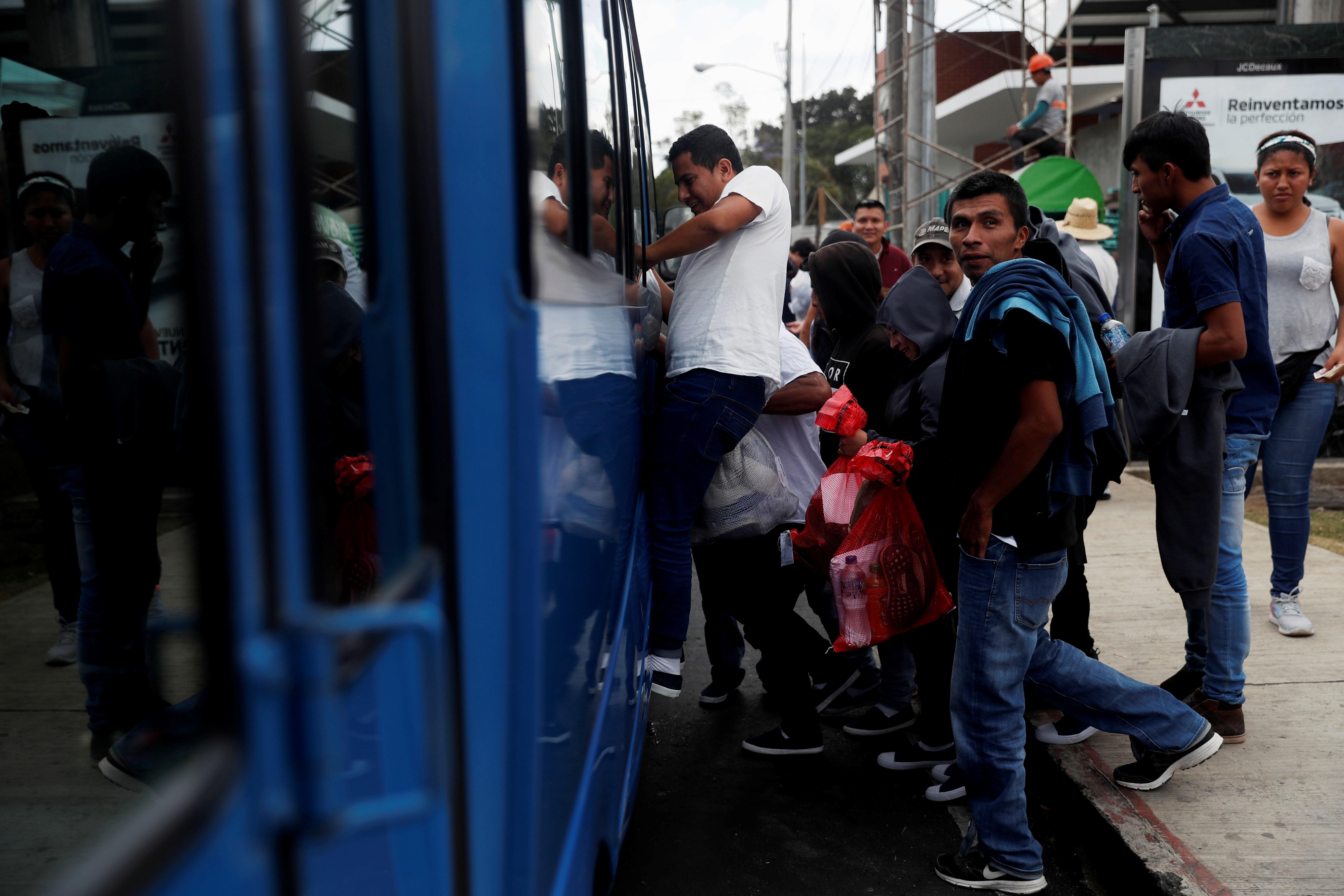Migrantes abordan un bus en las afueras de la Fuerza Aérea que los llevará a sus departamentos de origen. El Ministerio de Relaciones Exteriores ya cuenta con un programa de transporte; Conamigua implementará otro. (Foto Prensa Libre: EFE)