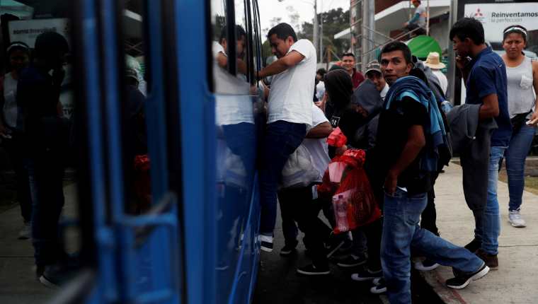 Migrantes abordan un bus en las afueras de la Fuerza Aérea que los llevará a sus departamentos de origen. El Ministerio de Relaciones Exteriores ya cuenta con un programa de transporte; Conamigua implementará otro. (Foto Prensa Libre: EFE)