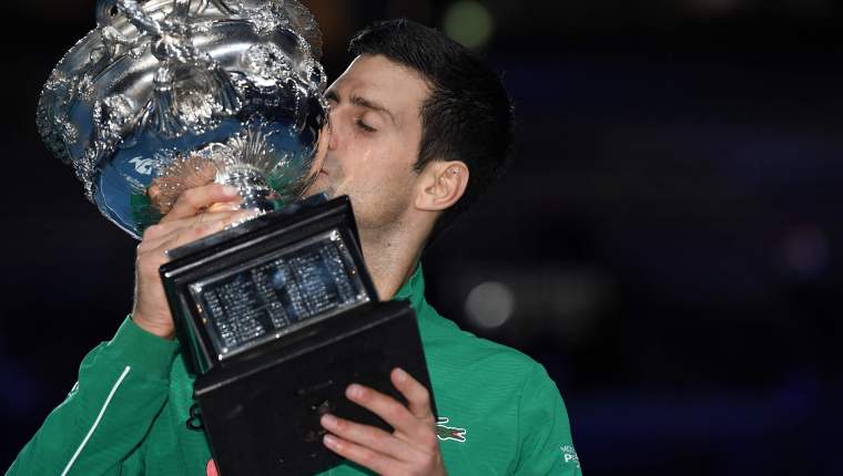 El serbio Novak Djokovic besa el trofeo de la Norman Brookes Challenge Cup después de vencer al dominico Austriaco Dominic Thiem en su último partido de singles masculinos. (Foto Prensa Libre: AFP)