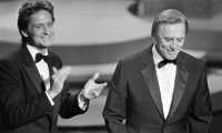 (FILES) In this file photo taken on March 25, 1985 US actor Michael Douglas (L) applauds his father US actor Kirk Douglas during the 57th Annual Academy Awards, in Hollywood, California. - US silver screen legend Kirk Douglas, the son of Jewish Russian immigrants who rose through the ranks to become one of Hollywood's biggest-ever stars, has died at 103, his family said on February 5, 2020. (Photo by ROB BOREN / AFP)
