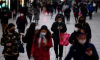 People wearing protective facemasks walk along a street in Shanghai on February 19, 2020. - The death toll from China's new coronavirus epidemic jumped past 2,000 on February 19 after 136 more people died, with the number of new cases falling for a second straight day, according to the National Health Commission. (Photo by NOEL CELIS / AFP) / China OUT