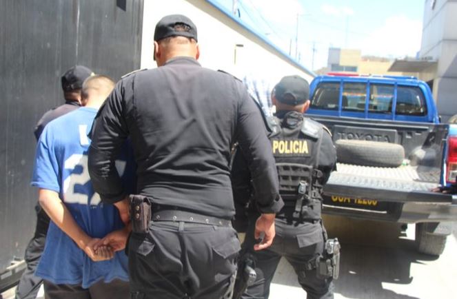Agentes de la PNC conducen al juzgado a dos menores que presuntamente atacaron al conductor de camión. (Foto Prensa Libre: Cortesía) 