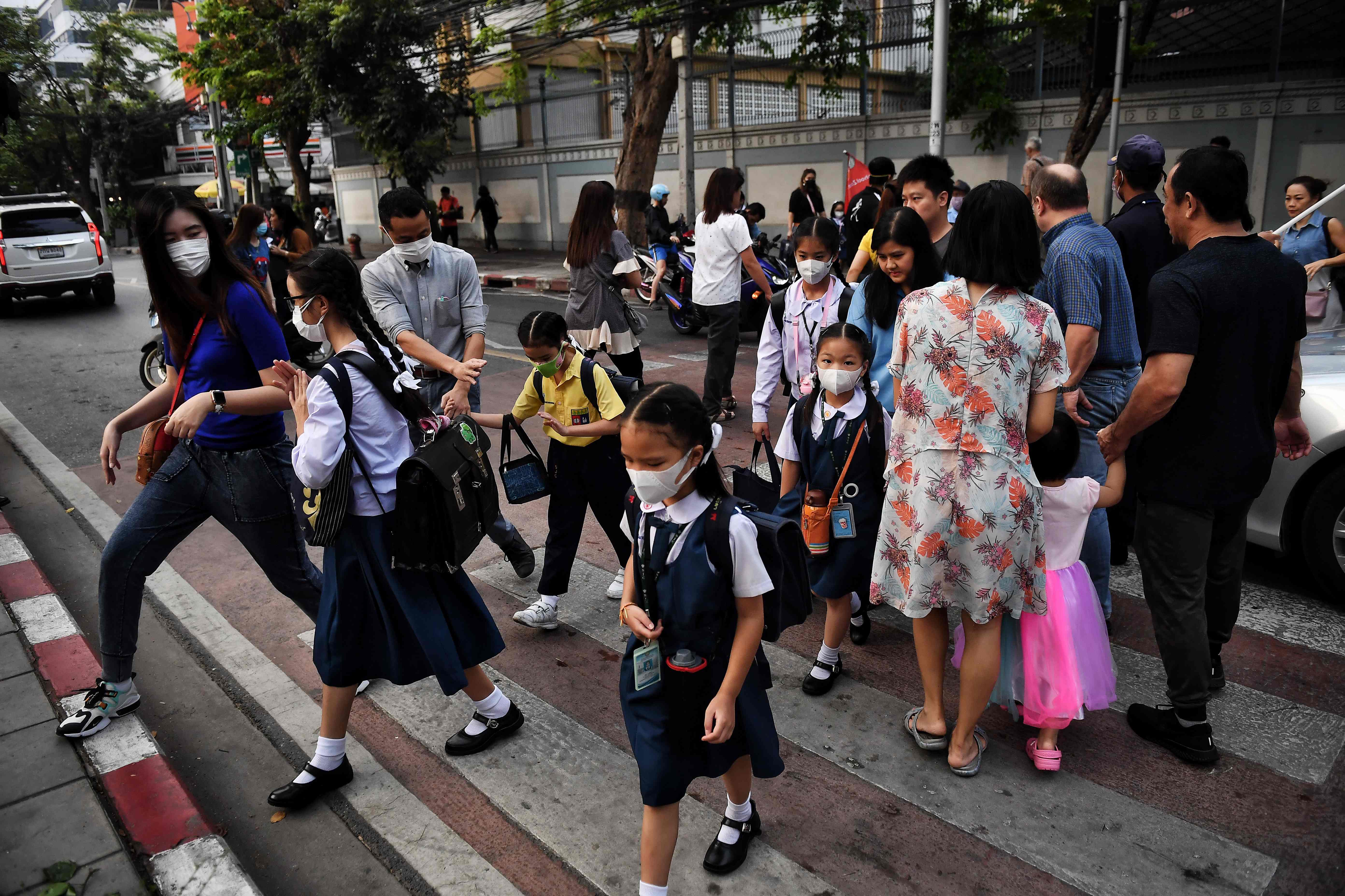 Usando mascarillas, padres llevan a sus hijos a la escuela en Bangkok. (Foto Prensa Libre: AFP)