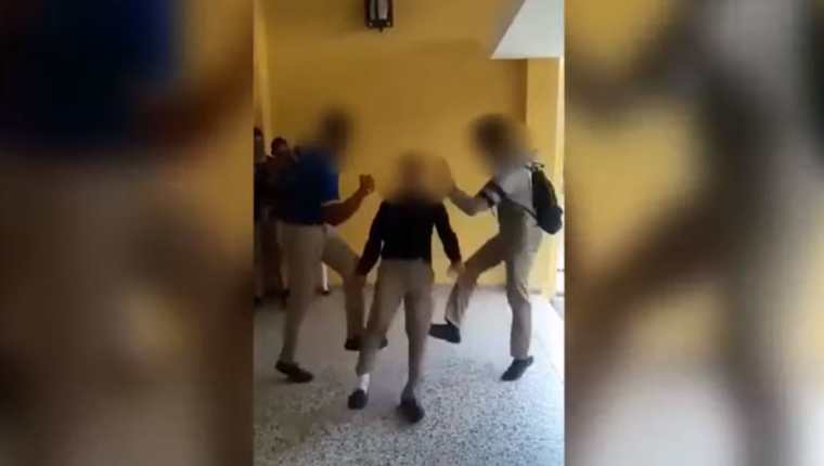 Imágenes en redes sociales muestran a tres alumnos que practican el reto, cuando el joven de en medio cae y le rebota la cabeza en el piso. (Foto Prensa Libre: Tomada de Youtube) 