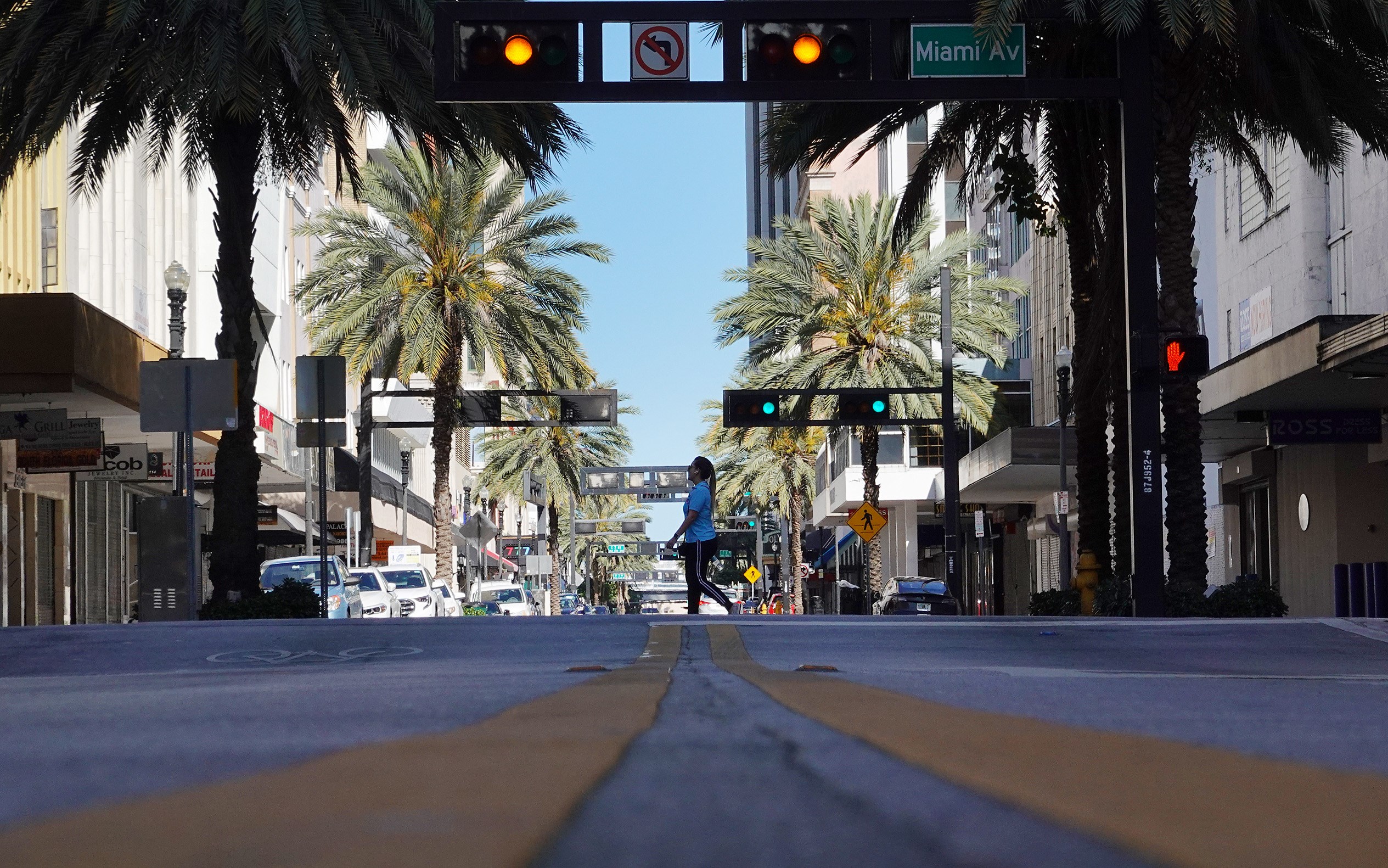 MIAMI, FL - MARCH 24: A pedestrian crosses a street void of much traffic as large numbers of people stay home in an effort to contain the coronavirus pandemic on March 24, 2020 in Miami, Florida. Across the country people are adapting to the new normal with protective gear, social distancing, businesses are restricting hours and restaurant owners are being asked to close except for pickup and delivery in an attempt to stop the spread of COVID-19.   Joe Raedle/Getty Images/AFP
== FOR NEWSPAPERS, INTERNET, TELCOS & TELEVISION USE ONLY ==