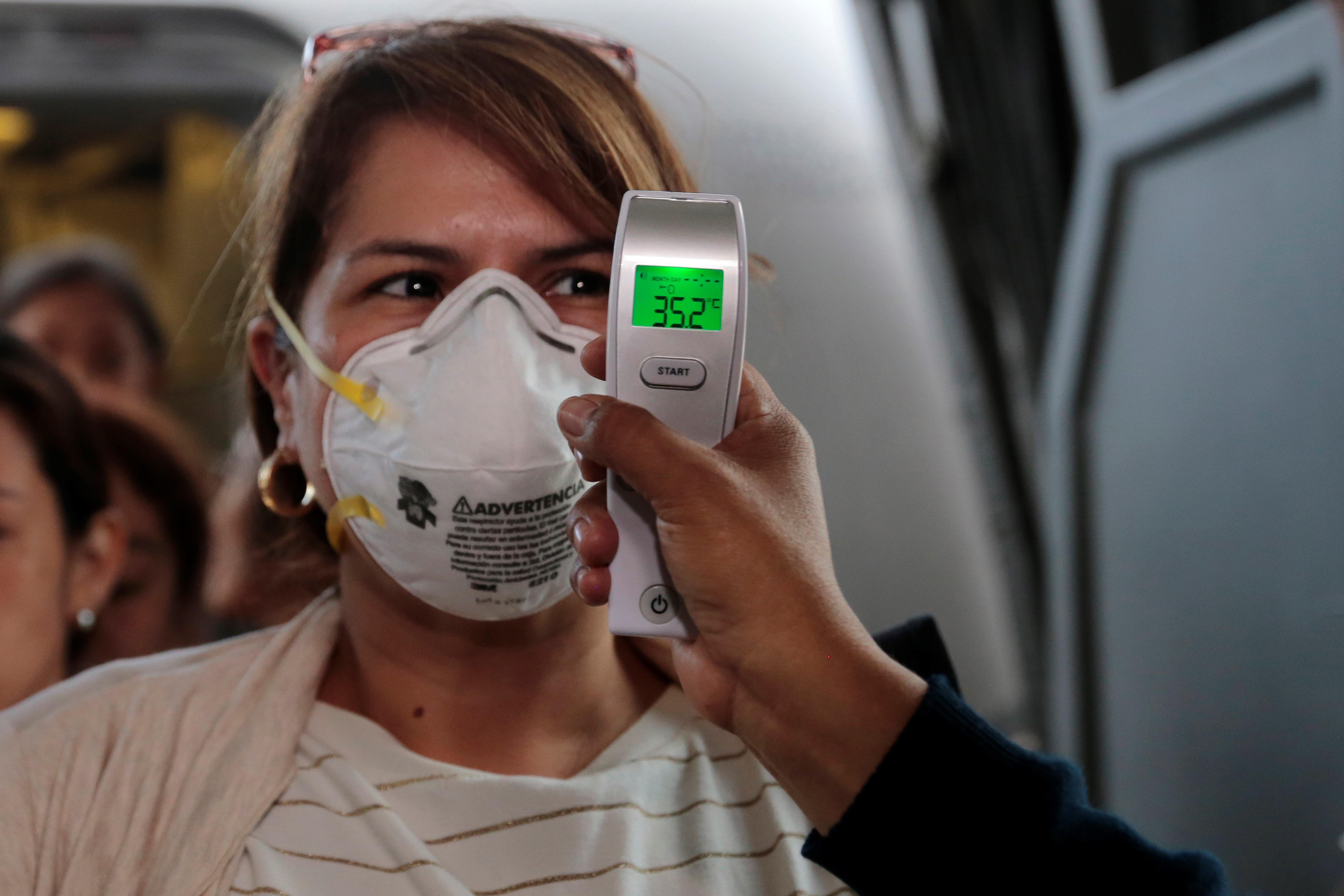 En el ingreso del Aeropuerto Internacional Aurora toman la temperatura a los viajeros como prevención del coronavirus. (Foto Prensa Libre: EFE)
