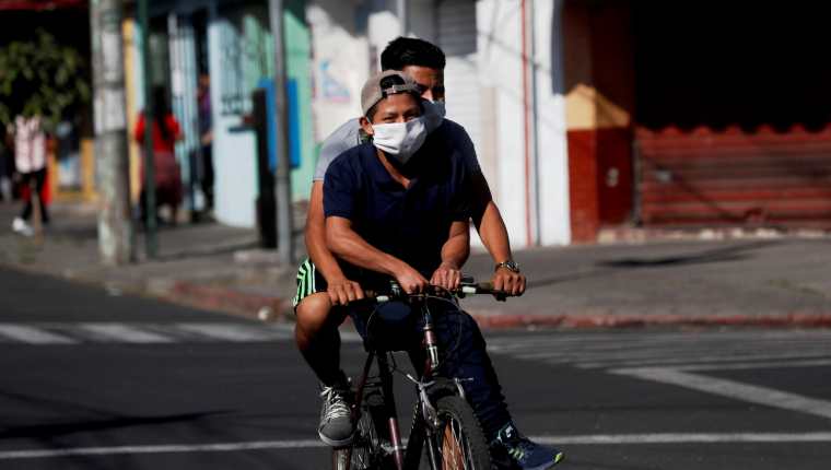 Jóvenes montan en una bicicleta antes del comienzo del toque de queda  en Guatemala. (Foto Prensa Libre: EFE)