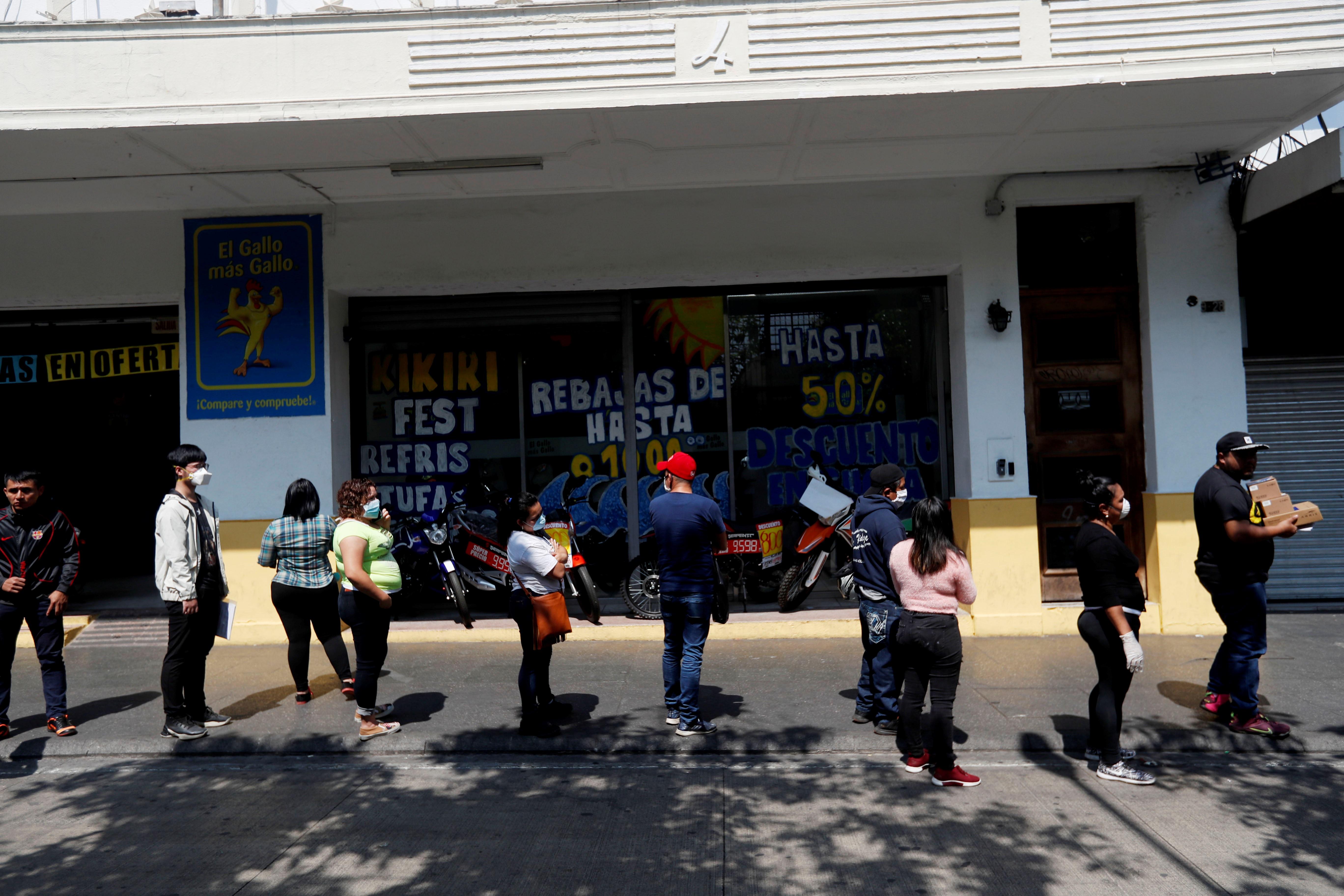 Personas hacen fila para entrar a un comercio de telefonía móvil, manteniendo distancia entre ellos para evitar el contagio de coronavirus, este martes en la zona 1 de la capital. (Foto Prensa Libre: EFE)