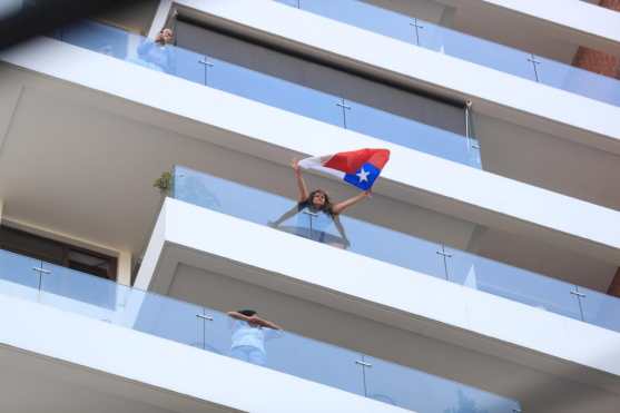 Una dama sacude una bandera de Chile mientras el concierto seguía afuera de los apartamentos. Foto Prensa Libre:  Juan Diego González
