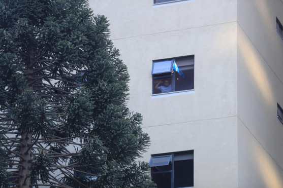 Desde lo más alto de uno de los edificios de apartamentos alguien muestra la bandera para alentar a los vecinos. Foto Prensa Libre: Juan Diego González