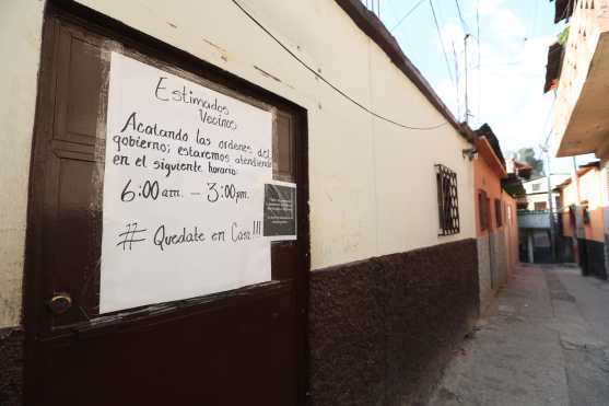 En una vivienda que presta servicios a la comunidad se anuncia a los vecinos del horario por el toque de queda. Foto Prensa Libre: Óscar Rivas