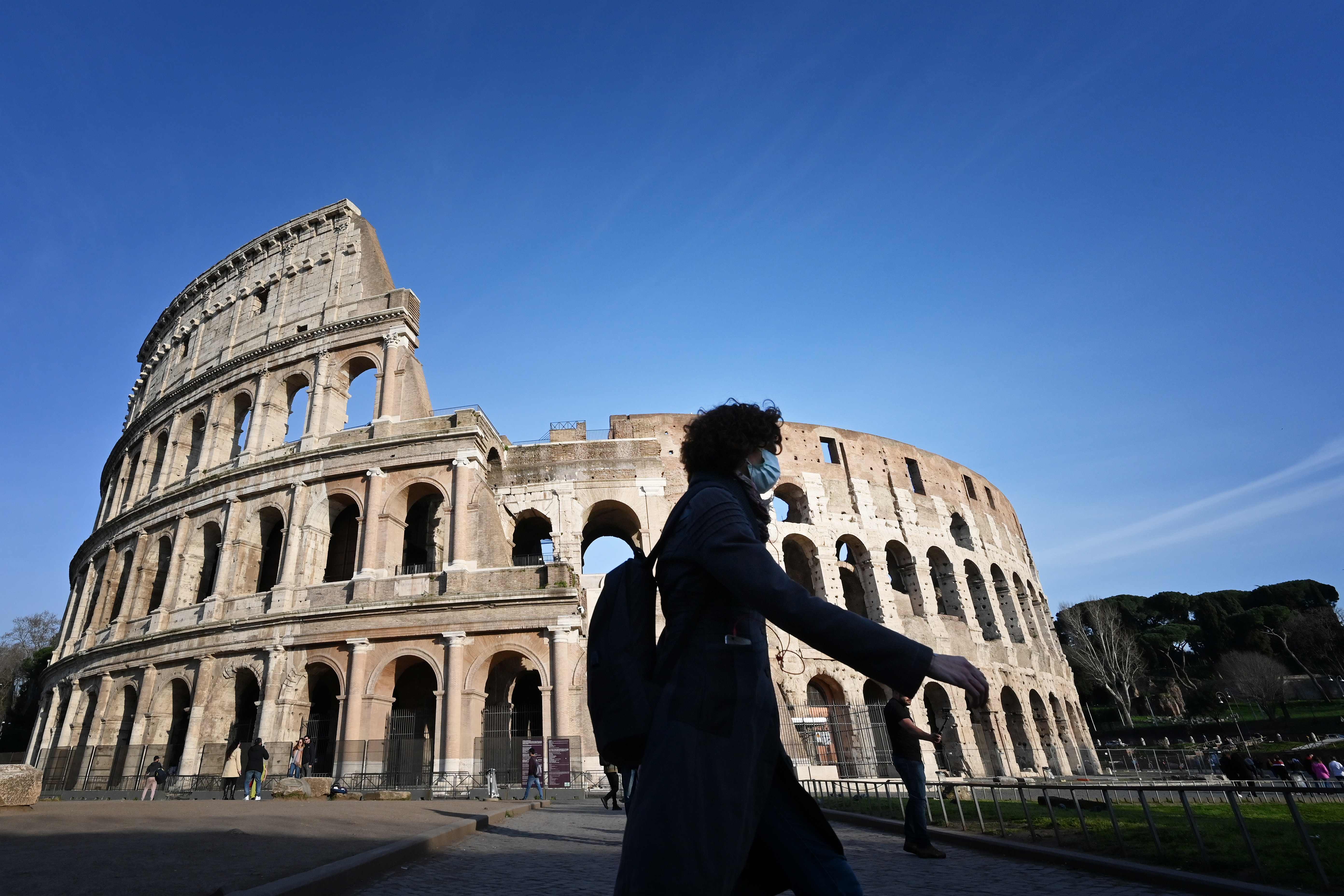 Una mujer con una mascarilla camina frente al histórico Coliseo de Roma en la capital italiana. (Foto Prensa Libre: EFE)