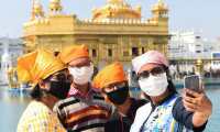 Devotees wearing a facemask amid concerns over the spread of the COVID-19 coronavirus take a selfie at the Golden Temple in Amritsar on March 17, 2020. (Photo by NARINDER NANU / AFP)