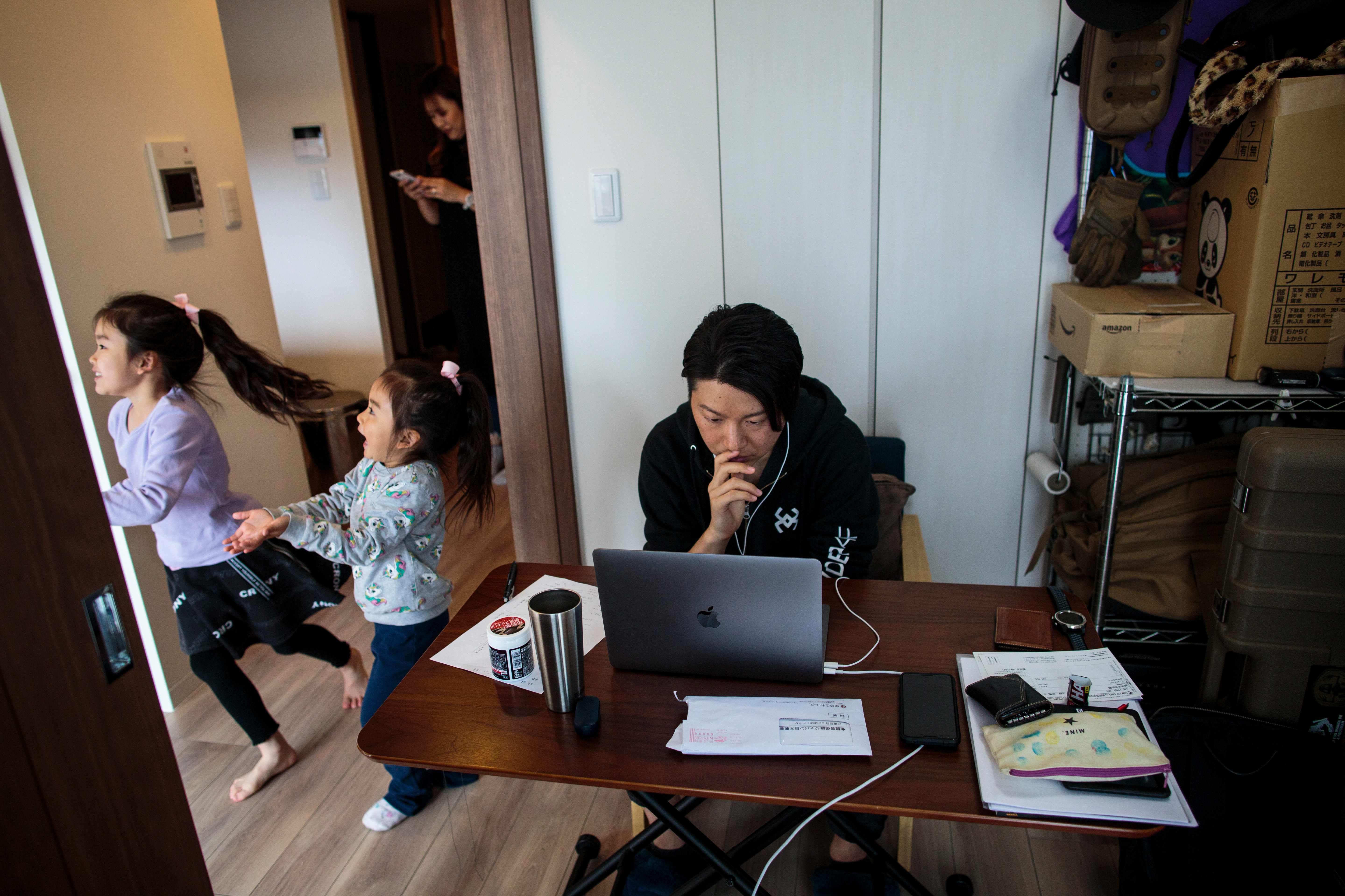 Teletrabajo con niños.
Mientras sus hijas corren por la habitación, el japonés Yuki Sato, empleado de una start-up, trabaja en casa frente a la pantalla y con auriculares.