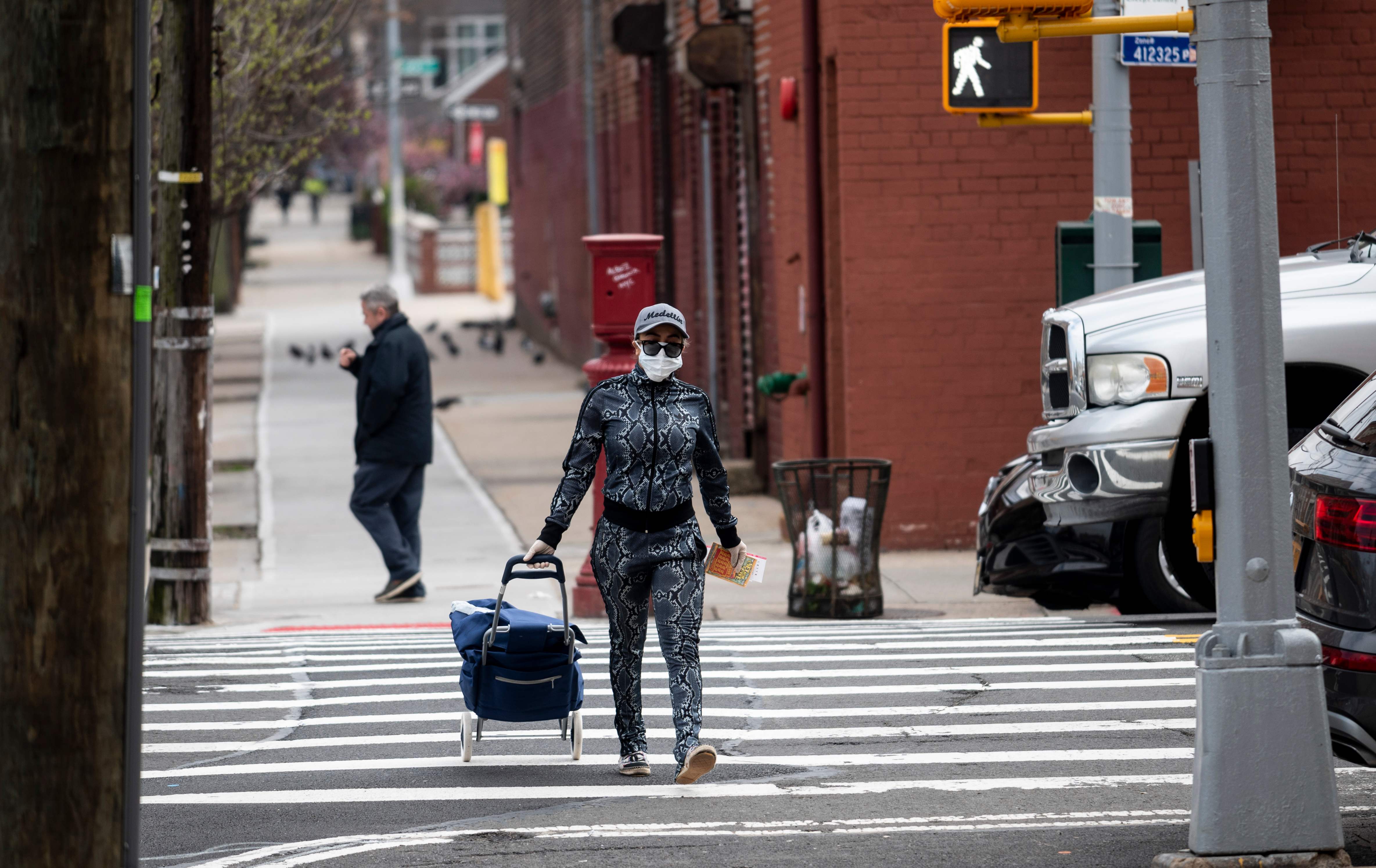 Una mujer camina por una calle solitaria en Nueva York, que usualmente se ven abarrotadas de transeúntes. Las personas solo salen a hacer compras. (Foto Prensa Libre: AFP)